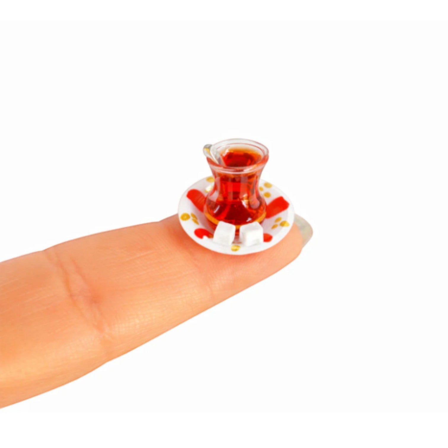 digitaley.co handmade miniature Turkish tea set with sugar cubes on a red and white patterned saucer, placed on a fingertip.