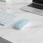 digitaley.co pastel blue wireless keyboard and mouse set with white keys and scroll wheel on a marble desk.